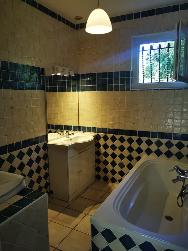 Salle de bain nettoyée, carrelage damier jaune et bleu marine, baignoire et lavabo — Mios 2026