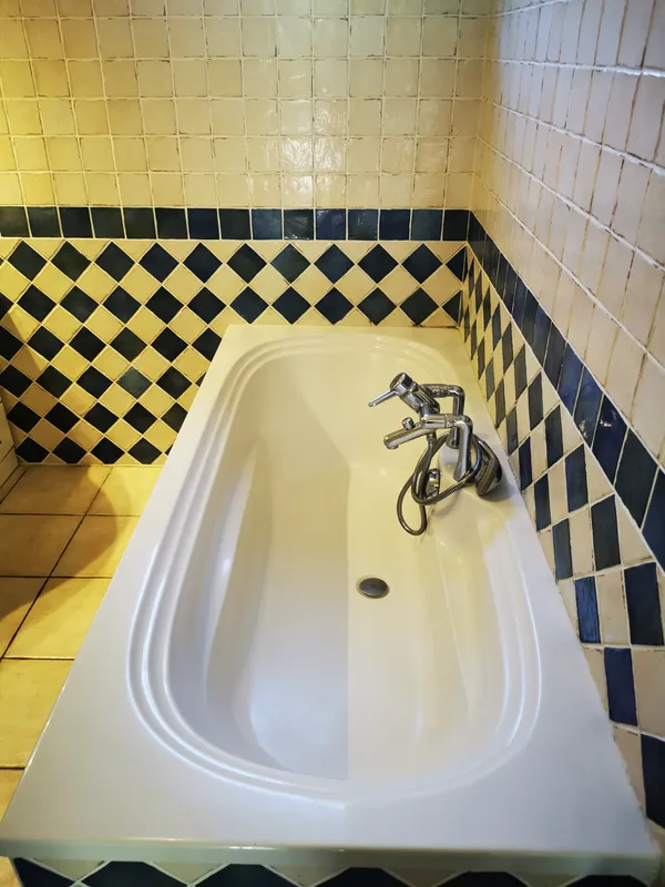 Baignoire nettoyée, carrelage damier jaune et bleu — avant aménagement Mios, mai 2026