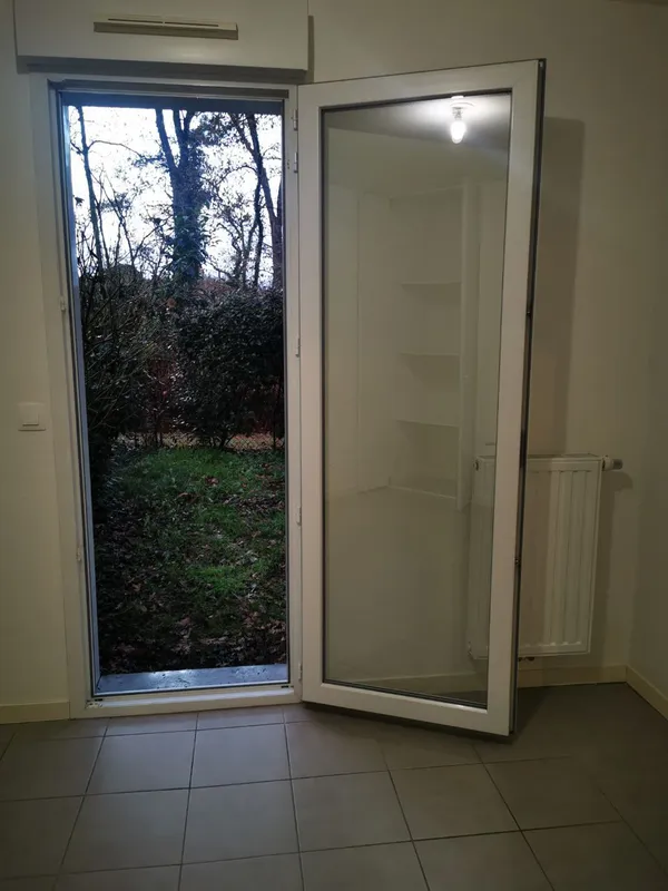 Chambre nettoyée avec porte-fenêtre sur jardin et radiateur, T2 Canéjan 2025
