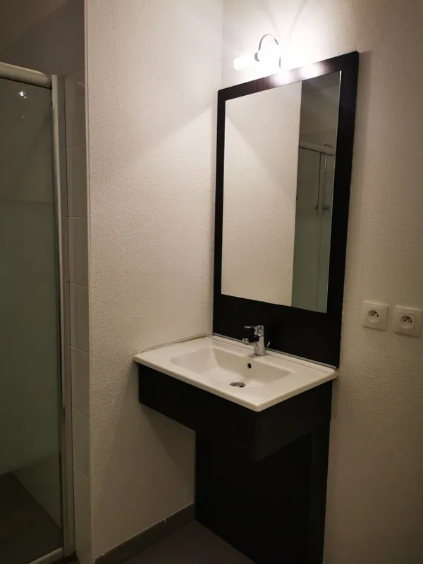 Meuble-vasque noir avec lavabo blanc et miroir éclairé nettoyés, salle de bain remise à neuf — Canéjan 2025