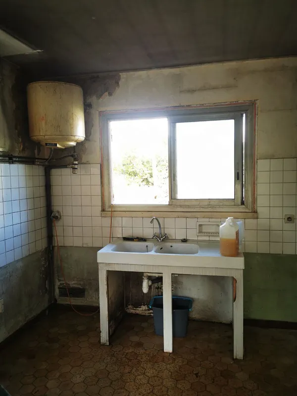 Cuisine très dégradée avec chauffe-eau, évier et carrelage noircis — état initial Léognan 2025